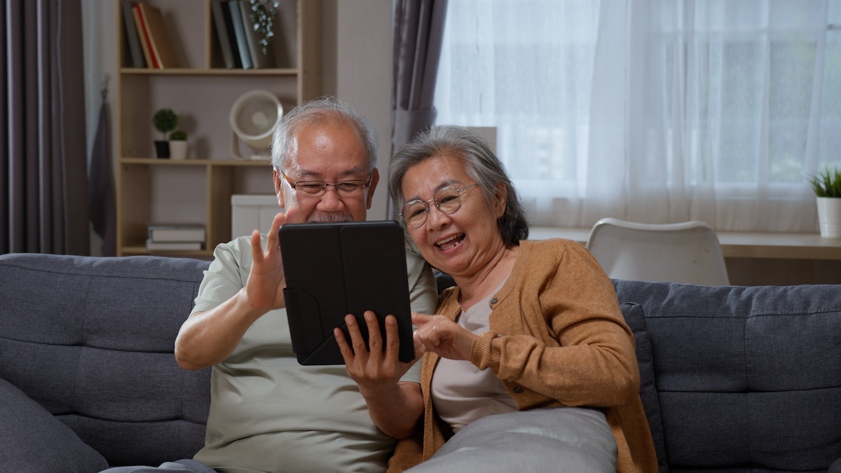 Senior Asian couple use a tablet touchscreen together at home